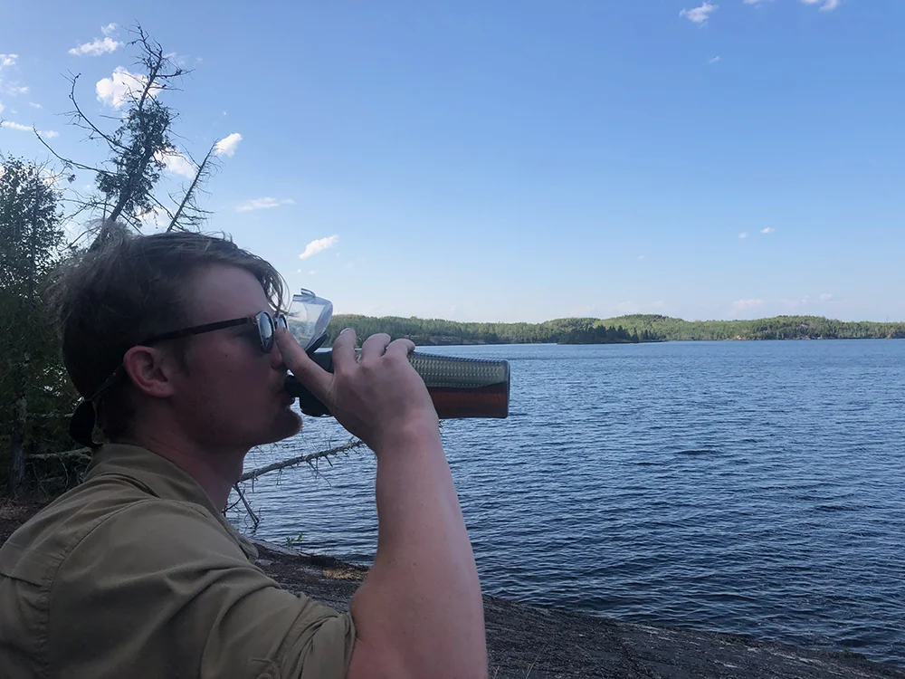 how to clean camping water containers - man drinking whiskey in the BWCA