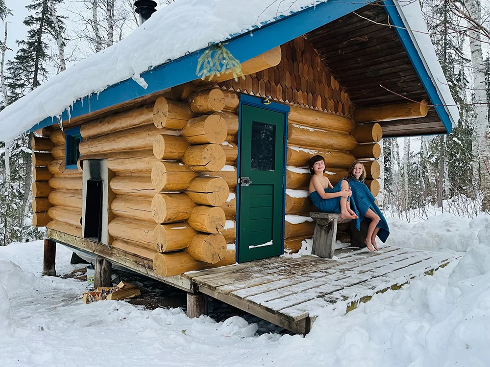 Ely, MN - Kids sitting in front of a traditional wood-buring sauna