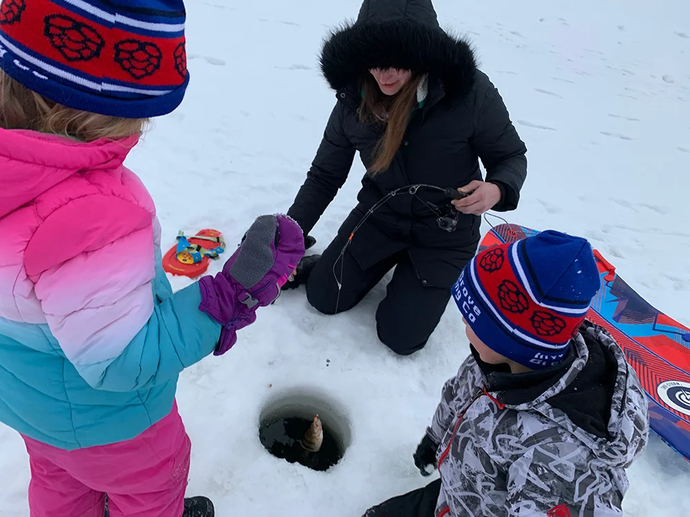 Kids pulling up a fish while ice fishing in Minnesota