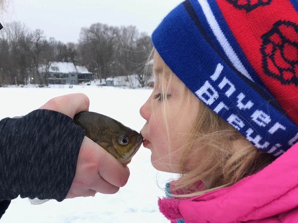 Ice Fishing Trips in Minnesota - Kid kissing a fish
