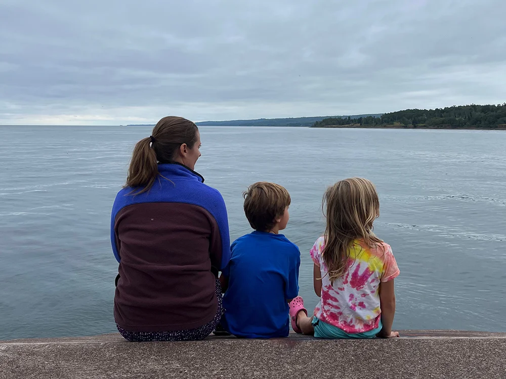 Best hikes on the North Shore MN - Kids and their mom sitting on the pier in Two Harbors, MN