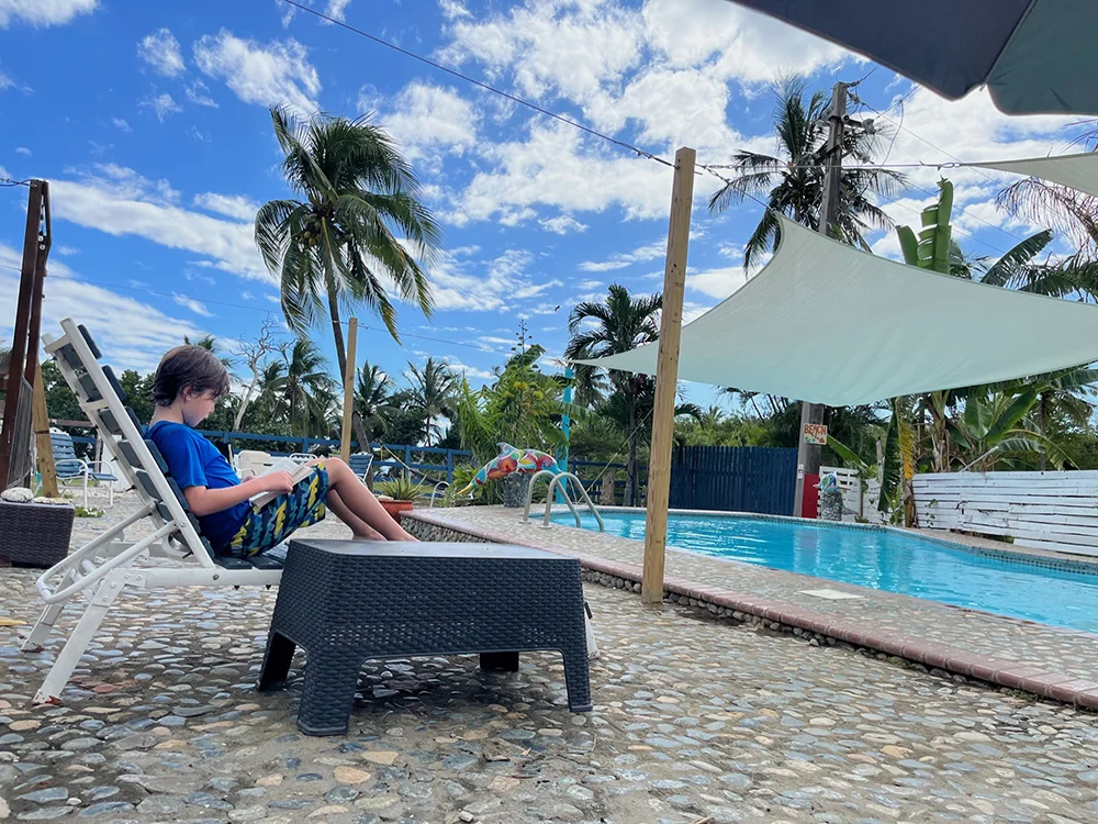 Kid reading at the pool at Finca Corsica, an Airbnb in Patillas Puerto Rico