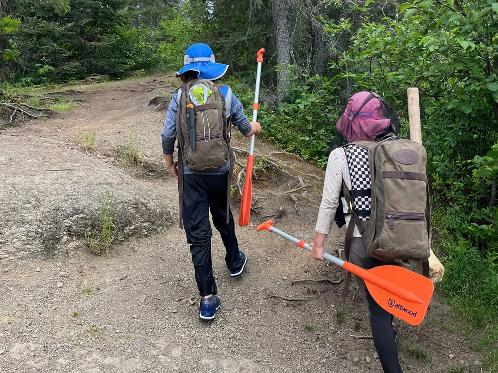 Camping Survival Kit for Kids - Two kids carrying their survival packs on a portage in the BWCA